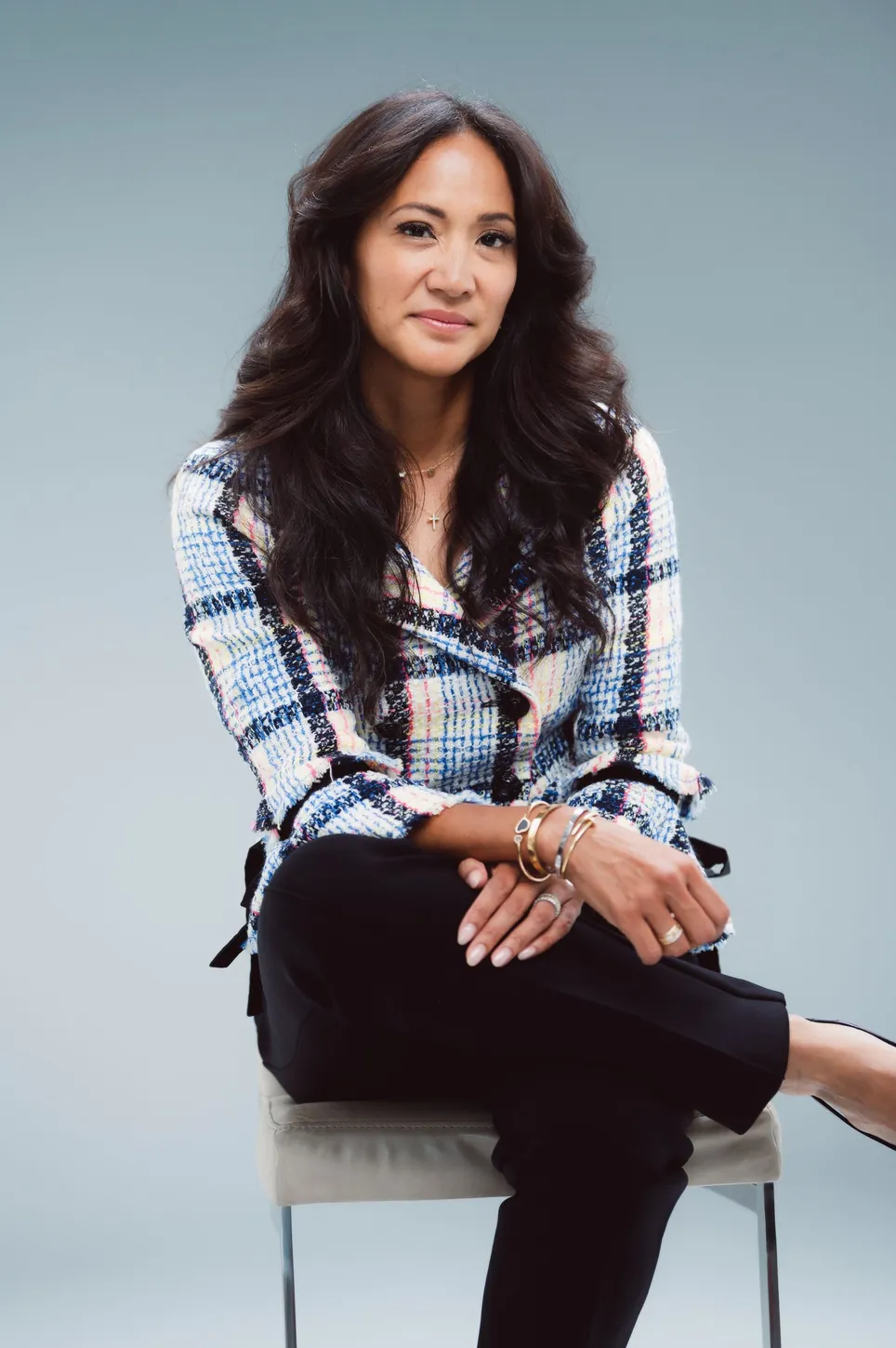 Dr. Valerie Woo seated on a stool, wearing a plaid blazer